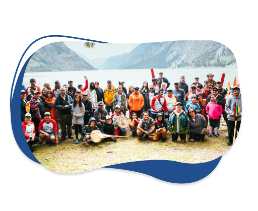 Group picture of people from community with lake and mountains in the background.