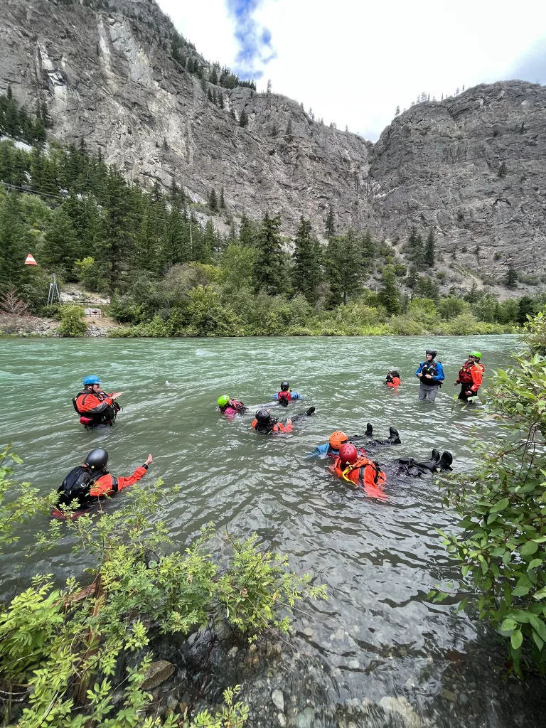 Group of people floating in river with mountains in the background.