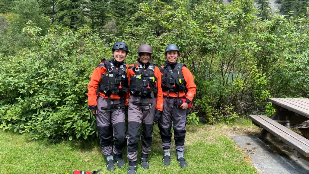 Group of three people standing in front of trees during Rescue Technician Level 2 training.